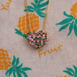 Close-up of golden heart pendant with colorful zircon stones on gold box chain