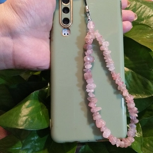 Pink crystal stone phone strap accessory with metal clasp shown in a natural outdoor setting
