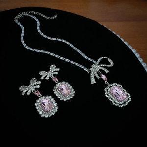 Parure de bijoux nœud argenté avec cristaux rectangulaires roses sur velours noir