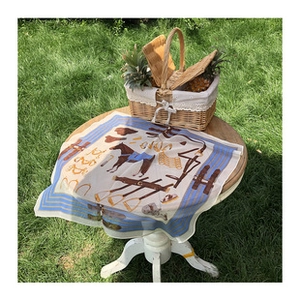 Detail of premium mulberry silk scarf with horse motif on outdoor picnic table setup