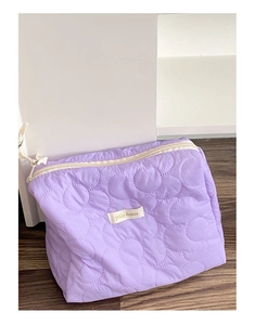 Détail macro du tissu matelassé violet avec motif floral 3D sur le sac à cosmétiques
