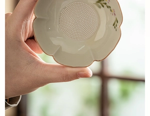Close-up of a hand-painted daisy ceramic tea strainer with a fine mesh filter