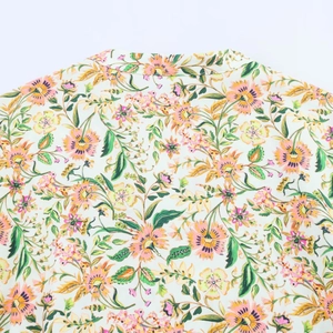 Detailopname van de oranje en roze bloemenprint op de stof van een midi-jurk
