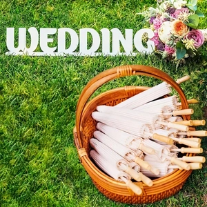 White wedding paper umbrellas in a woven basket on a green lawn with floral decor