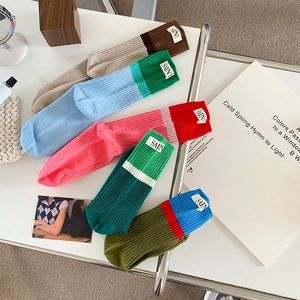Detail showing colorful patchwork cotton socks with custom SAIN label on white desk