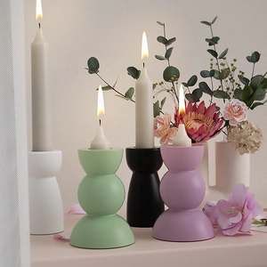 Macro detail of matte ceramic candle holders in pastel tones with elegant curved geometry