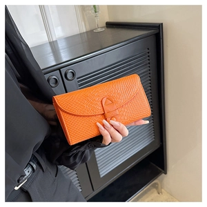 Detail of bright orange faux crocodile leather texture on stylish women's short wallet