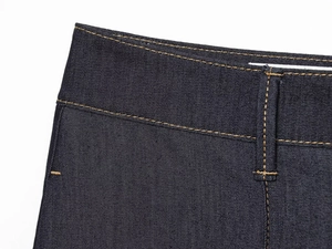 Détail des passants de ceinture et surpiqûres contrastées sur jean bleu indigo