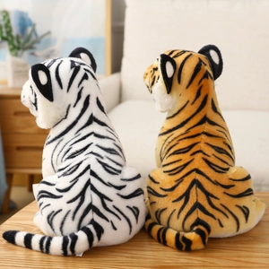 Rear view of lifelike plush tiger dolls in white and yellow sitting on a wooden table