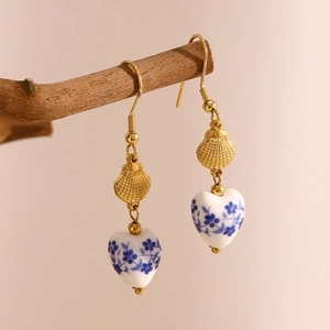 Detail of vintage heart ceramic earring with blue floral pattern on wooden branch