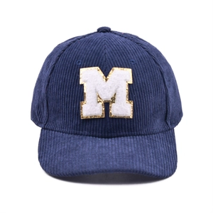 Detail einer marineblauen Cord-Baseballkappe mit weißem M-Patch und goldenem Glitzer