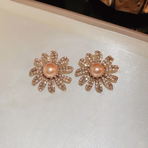 Detailed close-up of gold floral earrings with pink pearl centers and amber crystal petals