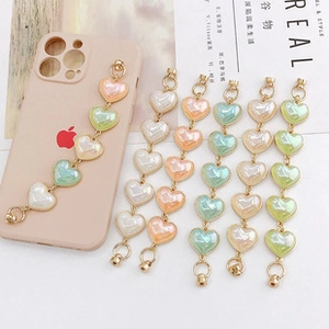 Macro detail of heart-shaped macaron bead phone straps with gold metal clasps
