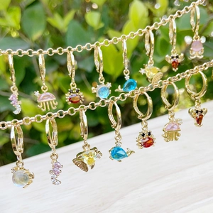 Close-up of golden ocean-themed earrings featuring colorful zircon sea creature charms