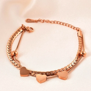 Detail of double-layer rose gold bracelet with heart charms on pink satin background