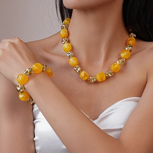 Detailed view of yellow acrylic geometric bead necklace and matching bracelet on a model