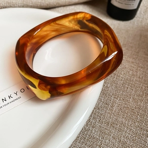 Brede geometrische armband van barnsteenhars met gladde vloeiende textuur