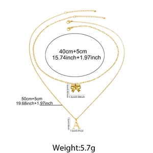 Detailed view of gold bow and letter A pendants with precise chain length and size specs