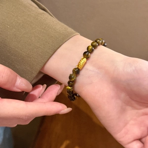 Detailed shot of tiger eye beaded bracelet with a 18K gold plated cat charm on wrist