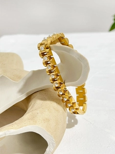 Detailed close-up of 18K gold watch-style chain bracelet with white pearl inlays