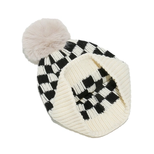 Detail of checkered knit beanie featuring a soft beige faux fur pompom and cuffed edge