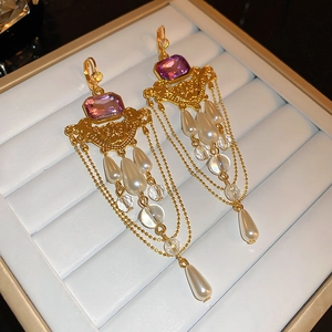 Détail de boucles d'oreilles vintage avec pierre violette et pampilles de perles