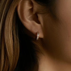 Close-up of 18K gold-plated small hoop earrings with square cubic zirconia on a model