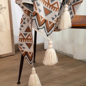 Close-up of bohemian knit blanket showing geometric patterns and soft tassels detail