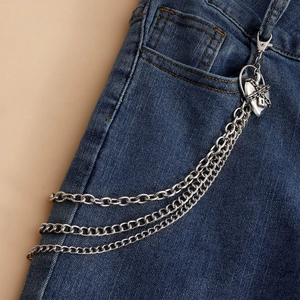 Detail view of multilayer silver metal trouser chain with heart charms on denim