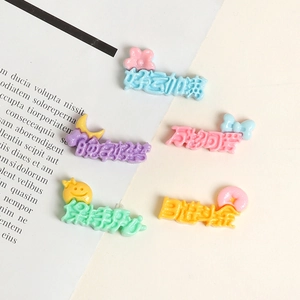 Close-up of five colorful resin DIY charms with cute cartoon patterns and Chinese text
