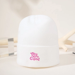 Detail of pink You are Good embroidery on white ribbed knit beanie hat folded cuff