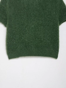 Dettaglio del maglione in maglia mohair verde muschio con morbida trama e bordo a coste