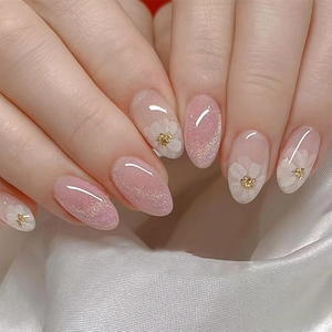 Detail of almond-shaped French press-on nails with 3D white flowers and nude pink gradient