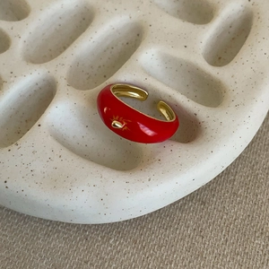 Detail of red enamel apple ring featuring golden sun relief and polished inner band