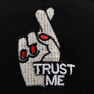 Black cotton baseball cap with heart gesture embroidery and TRUST ME text detail