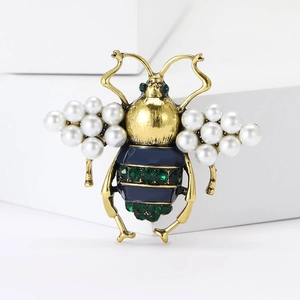 Detailed close-up of a vintage bee brooch featuring pearls and green crystal accents