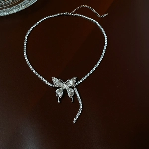 Detail showing crystal butterfly pendant and silver chain texture on dark background
