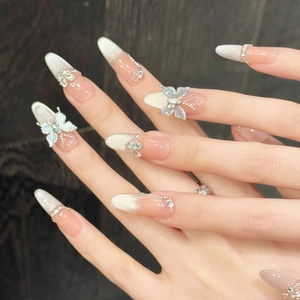 Nude pink gradient press-on nails with 3D butterfly, rhinestones, and cat-eye finish