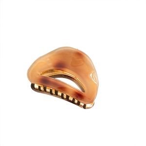 Minimalist acetate hair claw clip in amber tortoise shell pattern with gold metal hinge