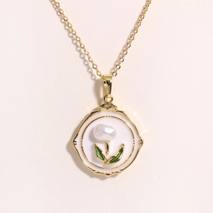 Detail of flower pendant with white enamel, central pearl, and green leaves on gold necklace