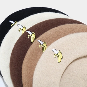 Detail of banana embroidery on wool beret hats in black beige and brown colors