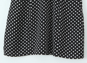 Détail de l'ourlet de la robe à pois blancs sur tissu noir doux et coutures