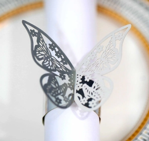 Close-up of a silver hollow butterfly napkin ring on a white napkin at a table