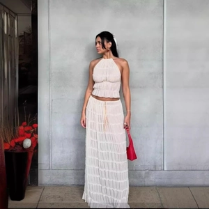 Detailed close-up of layered pleated texture on cream halter top and long skirt set