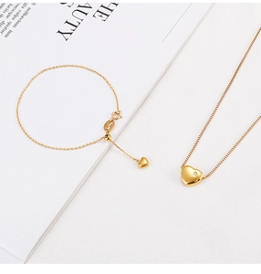 Detail of a gold heart-shaped jewelry set featuring a necklace and bracelet with zircon stones
