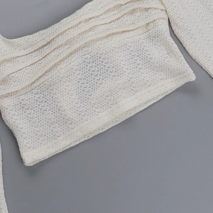 Gros plan sur l'encolure carrée et la texture de la dentelle ajourée de ce haut blanc cassé