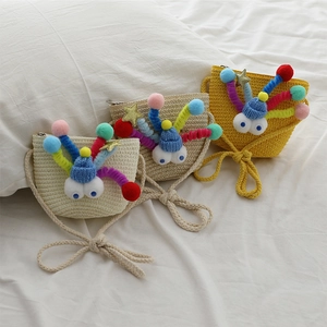 Three cute woven straw crossbody bags for kids with crochet doll decorations on white fabric