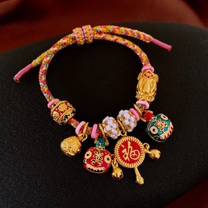 Détail d'un bracelet tissé main avec PiXiu doré, breloques en émail coloré et pendentif Fu