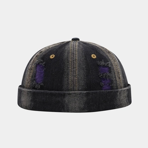 Close-up of distressed black denim docker hat with purple lining and yellow stitching
