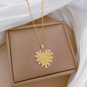 Detailed shot of golden heart-shaped Saint Benedict medal necklace with zircon stones